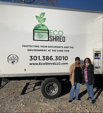 Two women standing infront of the EcoShred Shredding Truck